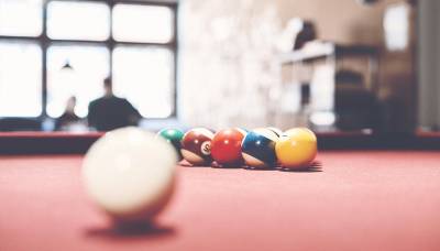 Pool table at the forefront and two colleagues chatting on the background